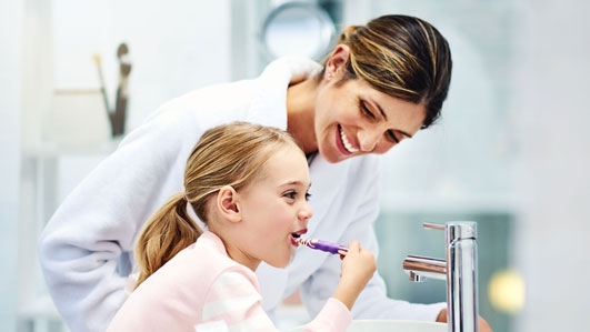 Mother and daughter brushing teeth